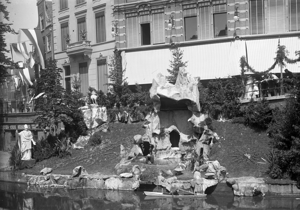 De uit cement vervaardigde grot met tuin op de werf voor het Kledingmagazijn Peek en Cloppenburg Deetman 1906