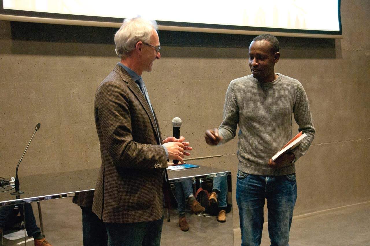Dick de Jong reikt het eerste jaarboek uit aan Abdisalam Yasin Ali